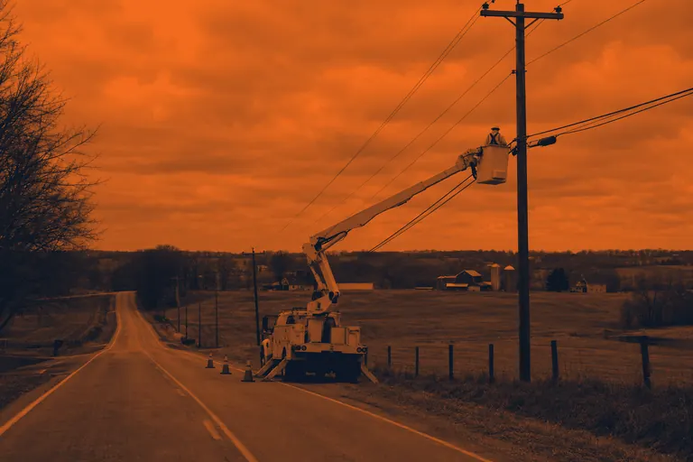 Bucket truck with its boom raised at a utility pole
